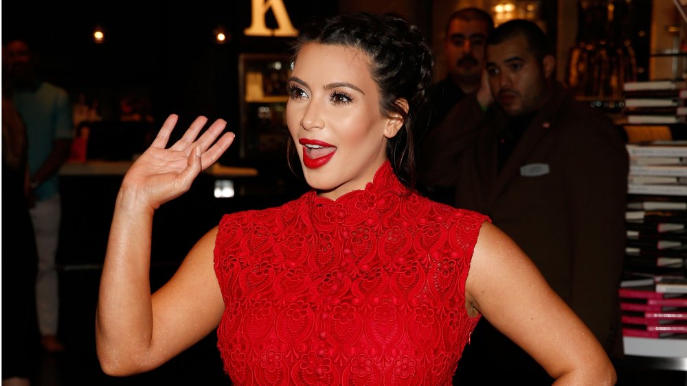 Kim Kardashian in abito rosso, agitando