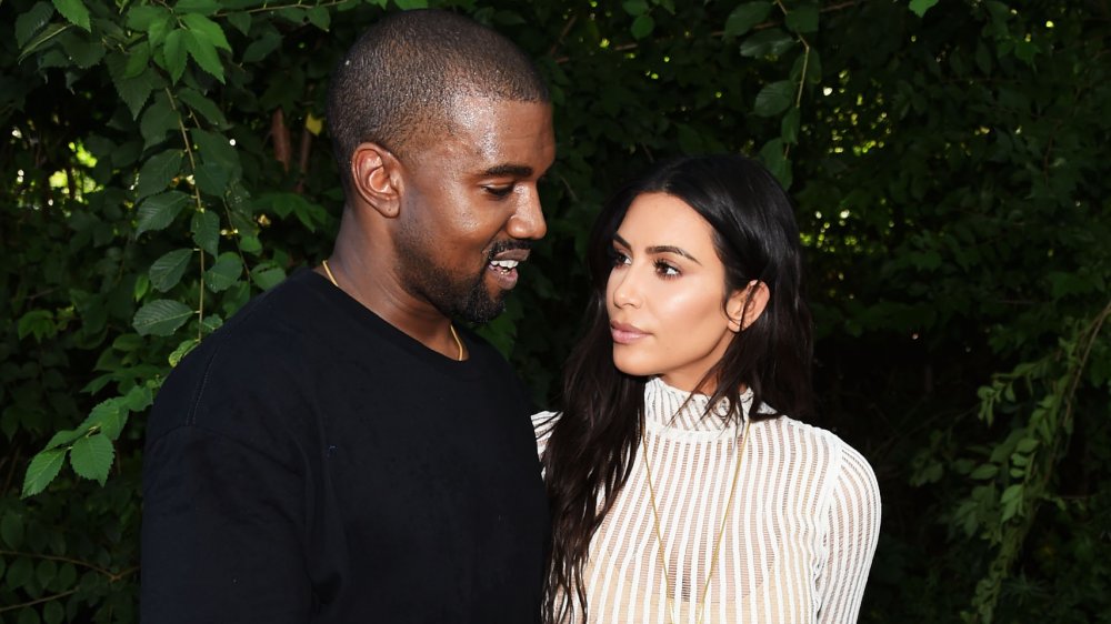 Kanye West e Kim Kardashian di fronte al verde, guardando l'un l'altro