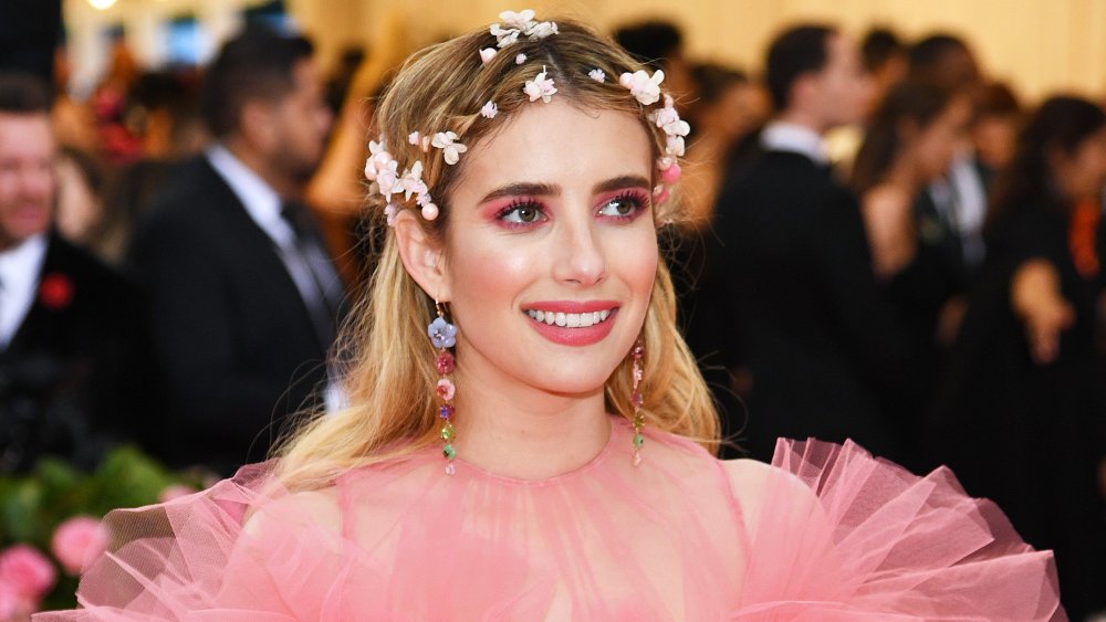 Emma Roberts in abito rosa e corona di fiori, sorridente