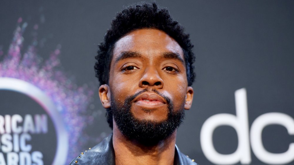 Chadwick Boseman in una giacca di pelle nera, in posa al AMAs con un'espressione neutra