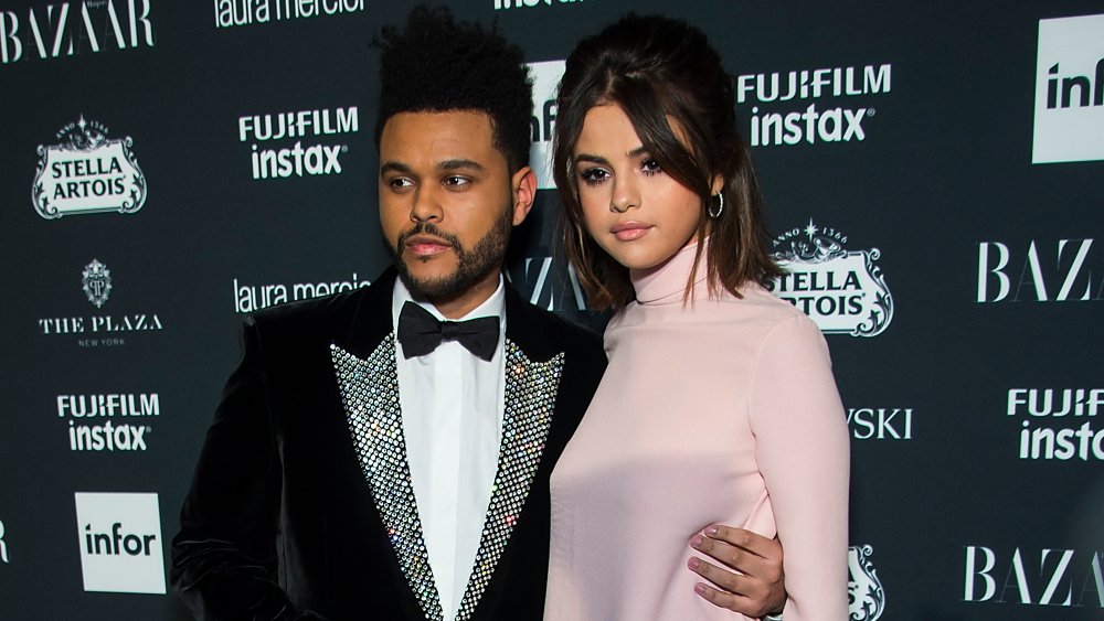 Il Weeknd in abito di velluto nero e papillon, Selena Gomez in abito rosa, in posa insieme sul tappeto rosso