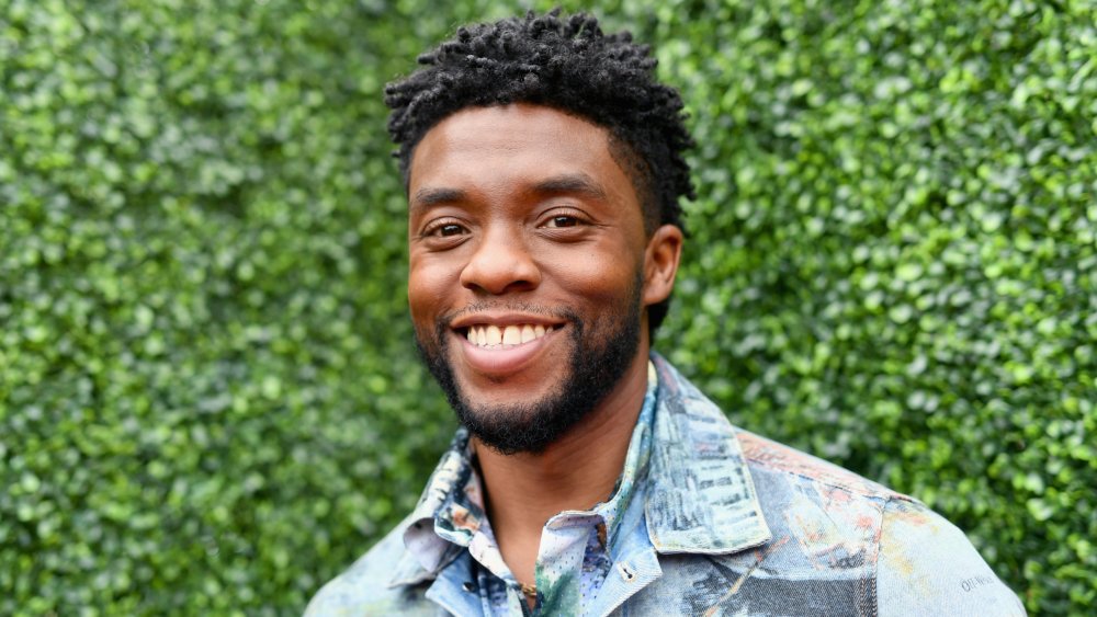 Chadwick Boseman in una giacca di jeans multicolore e button-up, sorridente fuori