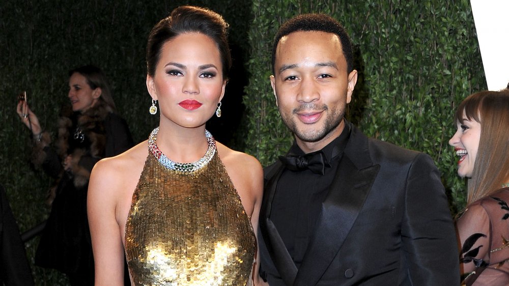 Chrissy Teigen in un abito d'oro in piedi con John Legend