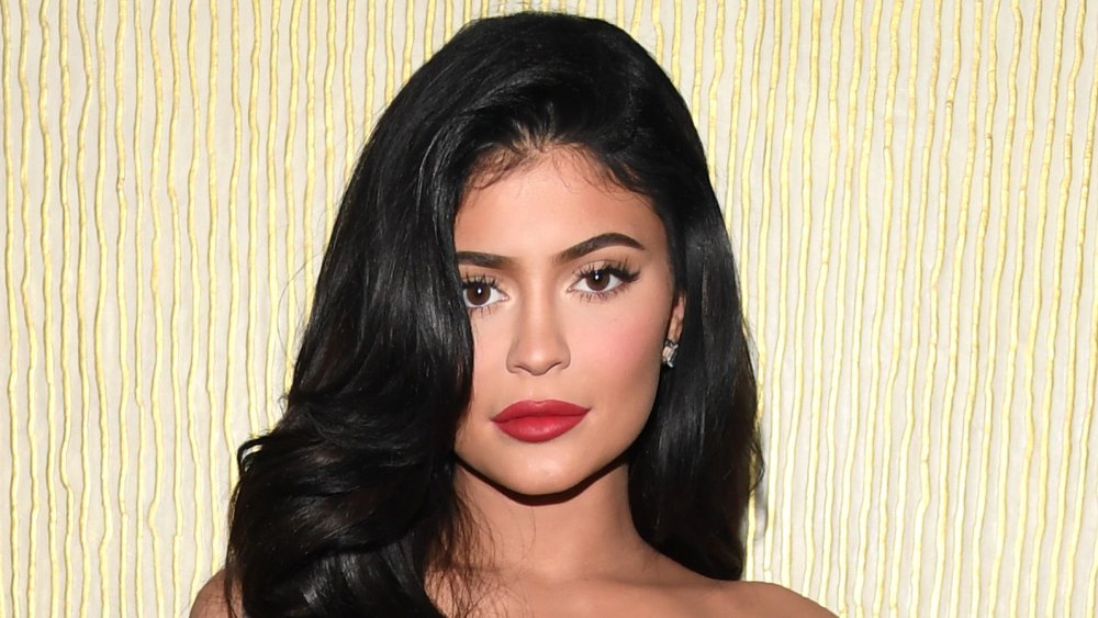 Kylie Jenner in abito rosso, in posa con un'espressione neutra