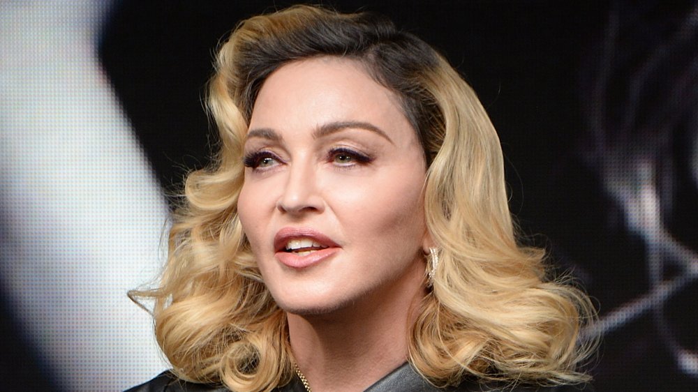 Madonna in un abito di pelle nera, parlando mentre si guarda di lato