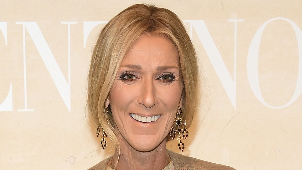 Céline Dion in un abito beige e orecchini penzolanti, sorridente grande