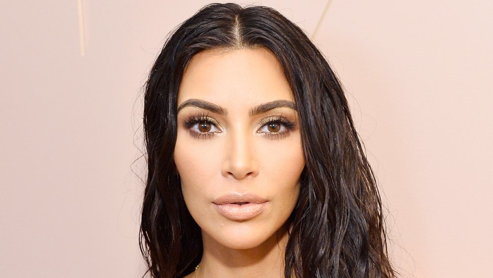 Kim Kardashian in abito bianco e capelli bagnati, in posa con un'espressione sorpresa