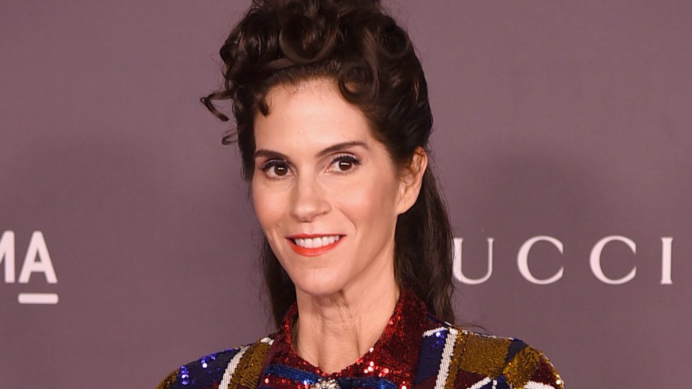 Jami Gertz in un abito scintillante rosso, blu e oro, sorridente e guardando fuori di lato