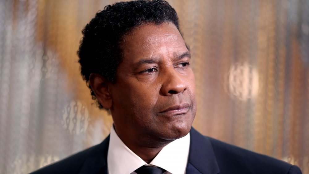 Denzel Washington in un classico abito nero e cravatta combo, guardando serio mentre guardando fuori di lato