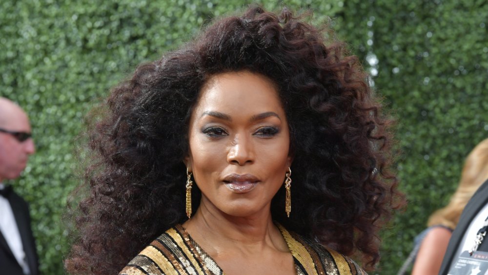 Angela Bassett in un abito a righe d'oro scintillante, in posa con un'espressione seria