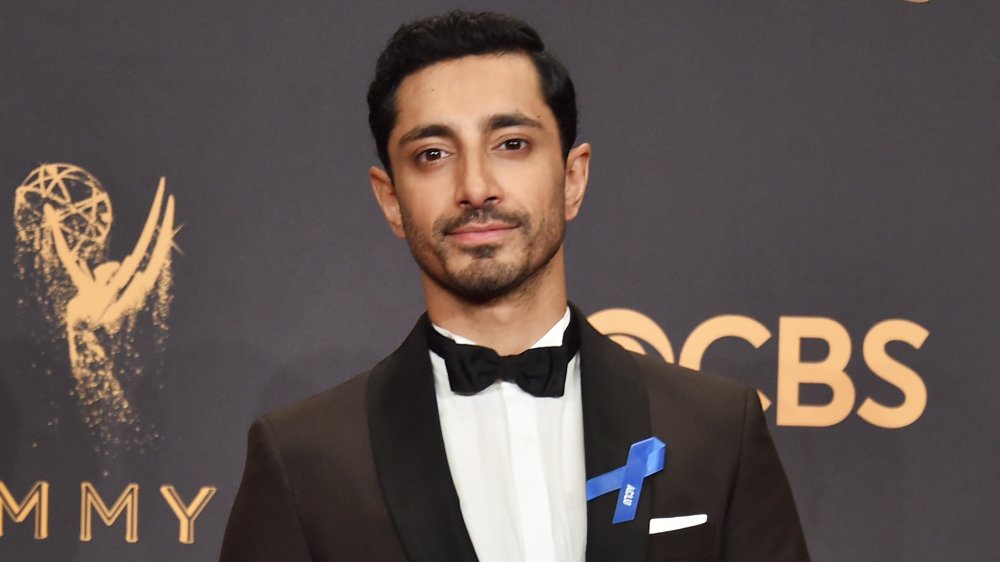 Riz Ahmed in abito nero e papillon, in posa con il suo Emmy