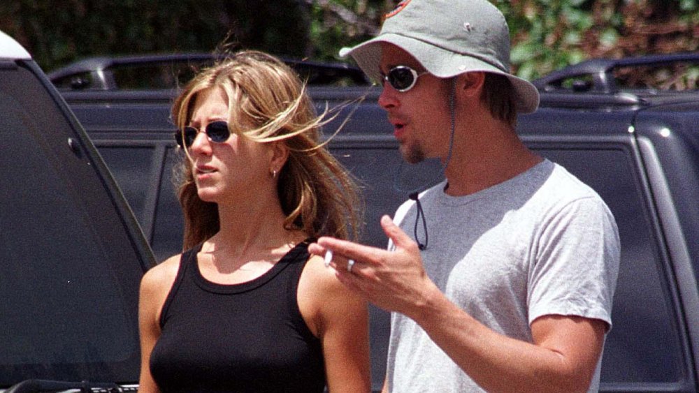 Jennifer Aniston e Brad Pitt, entrambi con gli occhiali da sole, che parlano mentre camminano in un parcheggio