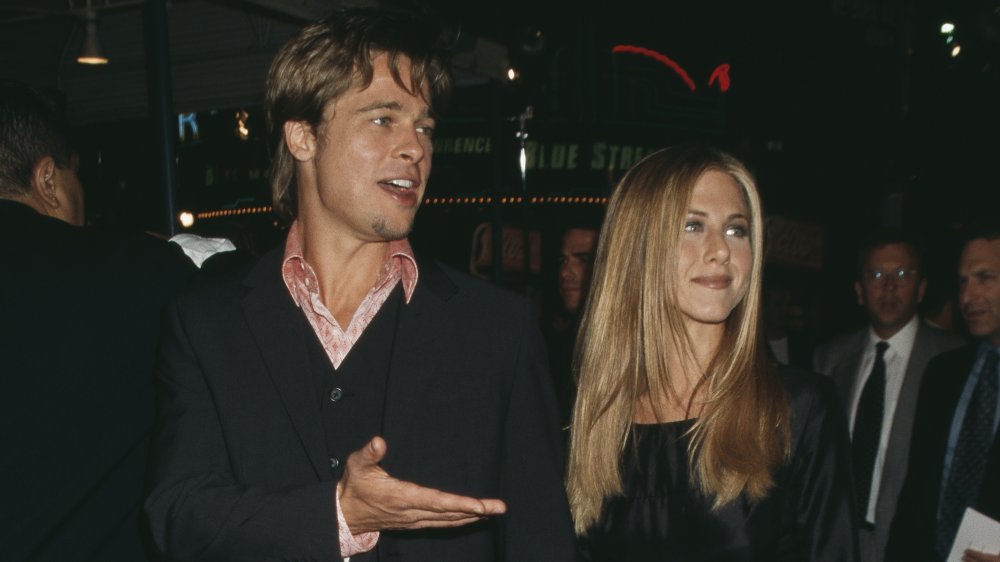 Brad Pitt e Jennifer Aniston, entrambi vestiti di nero, che si tengono per mano e camminano su un tappeto rosso