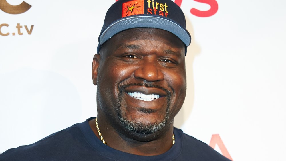 Shaquille O'Neal sorridente in una t-shirt blu e cappello