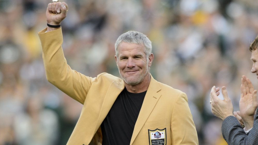 Brett Favre in un blazer giallo Hall of Fame, in posa con il pugno in aria in una partita