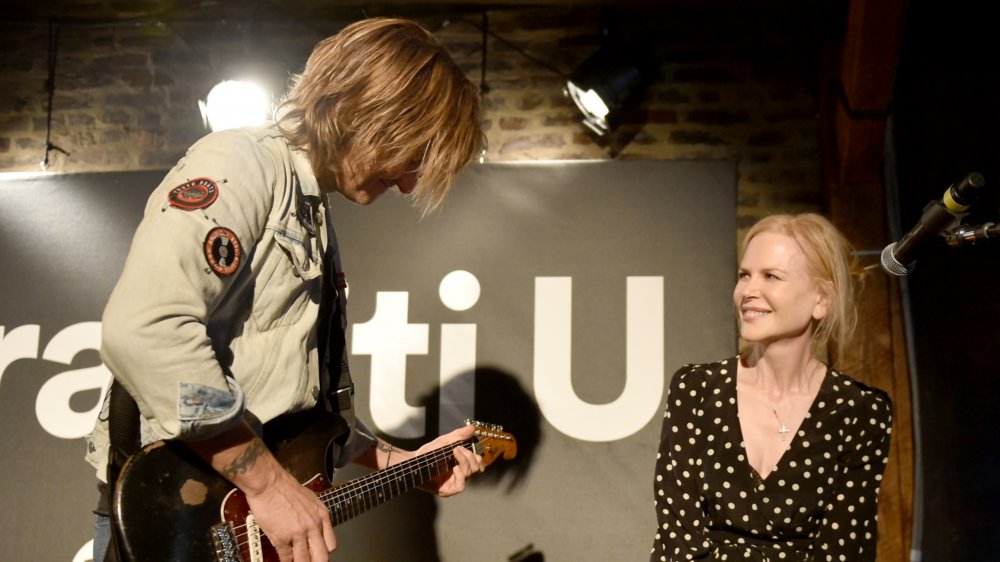 Nicole Kidman sorride mentre guarda Keith Urban suonare la chitarra