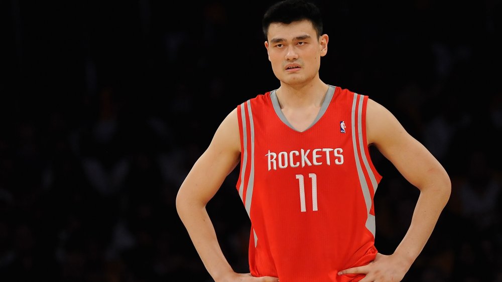 Yao Ming in piedi con le mani sui fianchi sul campo