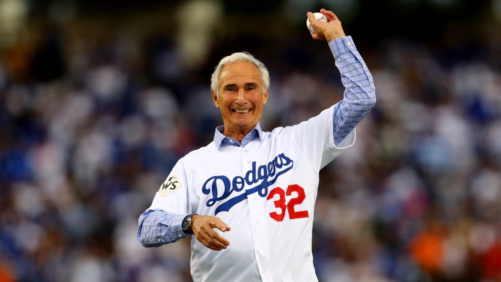 Un vecchio Sandy Koufax sorridente mentre lancia un lancio