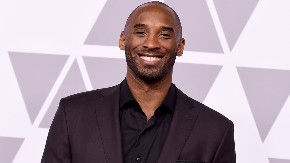 Kobe Bryant in abito tutto nero, sorridente