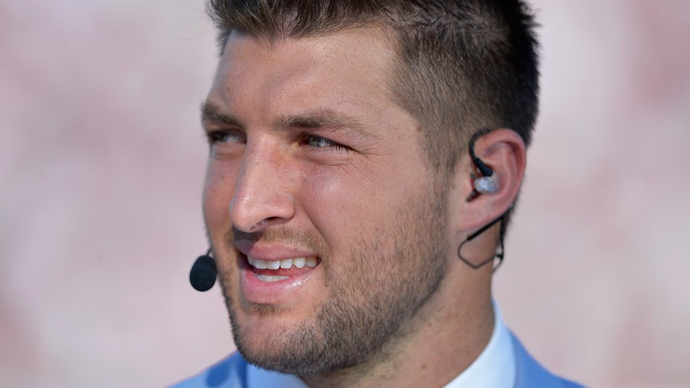 Tim Tebow parlando in un microfono, guardando fuori di lato