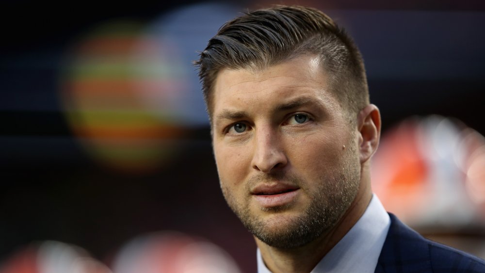 Tim Tebow in giacca e cravatta, con un'espressione seria