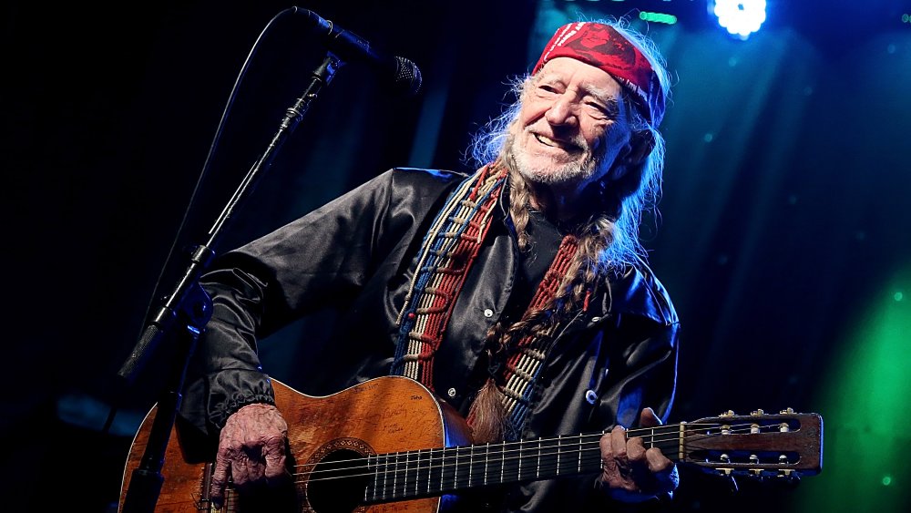 Willie Nelson sorridente mentre suona la chitarra