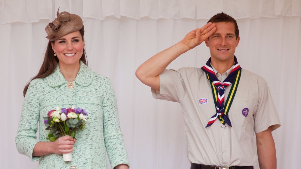 Bear Grylls saluta, in piedi accanto a Kate Middleton