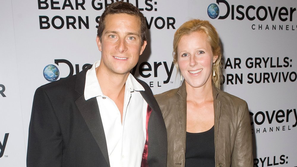 Bear Grylls e Shara Grylls di fronte al muro promo di Discovery