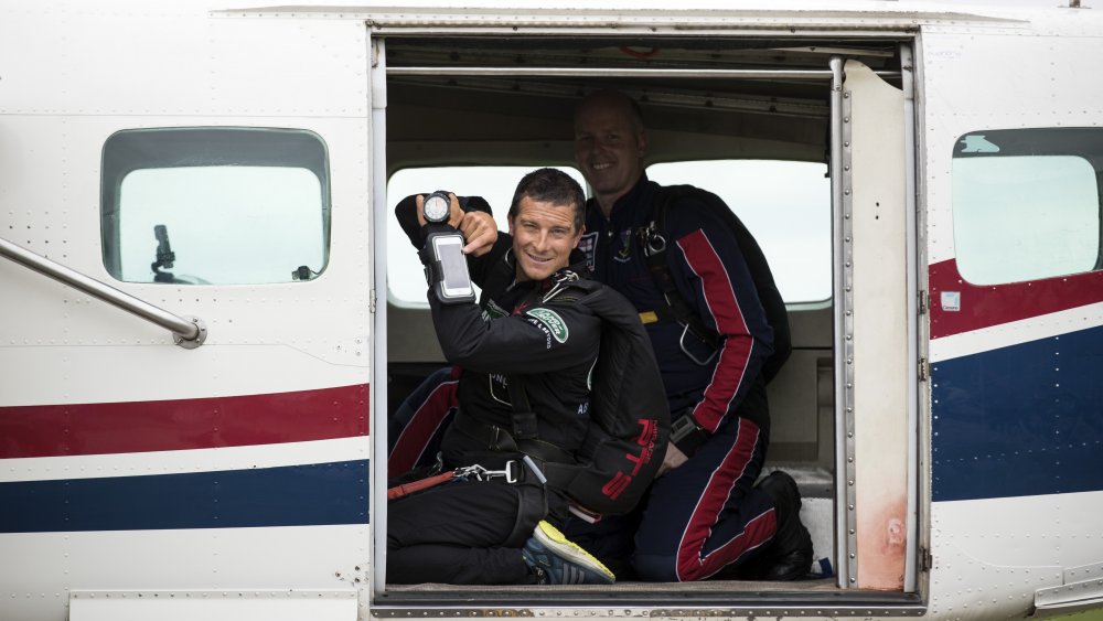 Bear Grylls in un aereo, in posa con il suo telefono