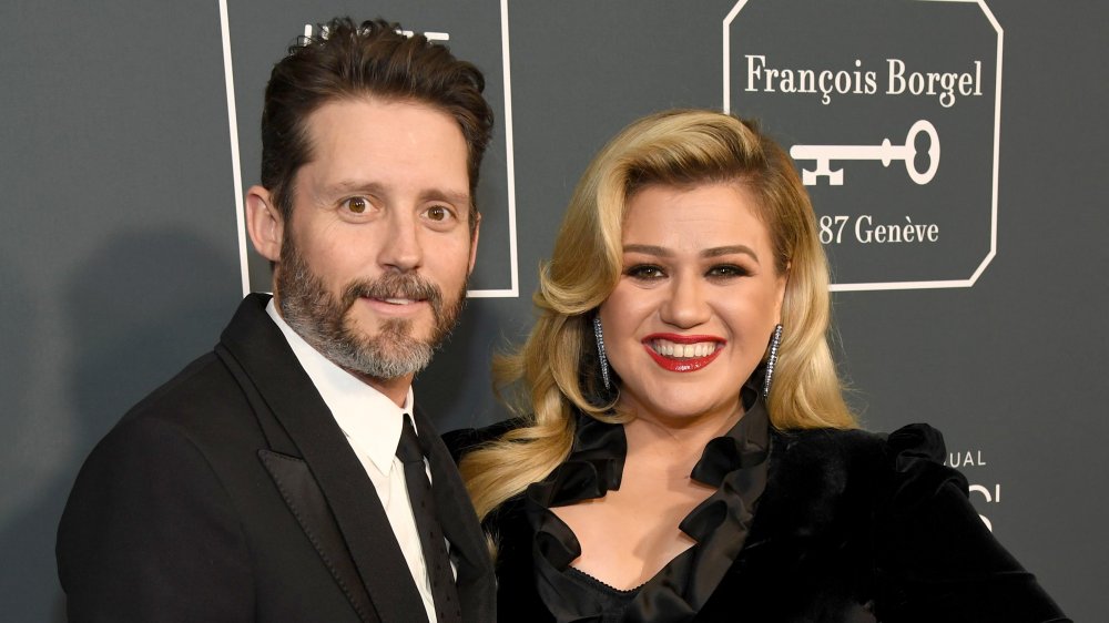 Brandon Blackstock e Kelly Clarkson, entrambi sorridenti mentre posano braccio a braccio sul tappeto rosso