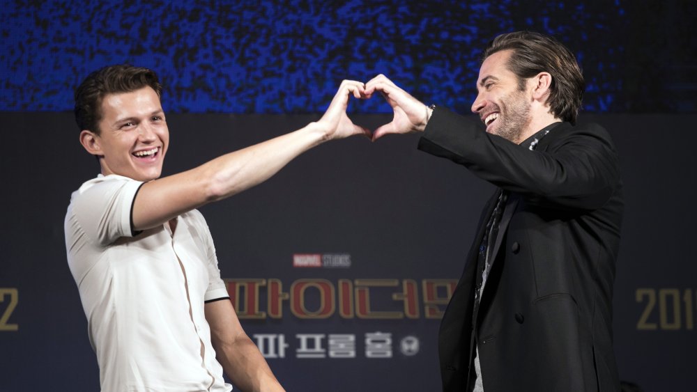 Tom Holland e Jake Gyllenhaal ridono mentre formano un cuore con le mani a un evento stampa Di Spider-Man: Far From Home