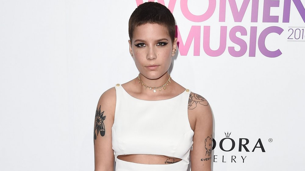 Halsey con i capelli corti scuri e tatuaggi sulle braccia