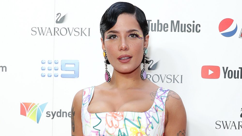 Halsey con capelli neri corti, trucco degli occhi colorato e orecchini lunghi