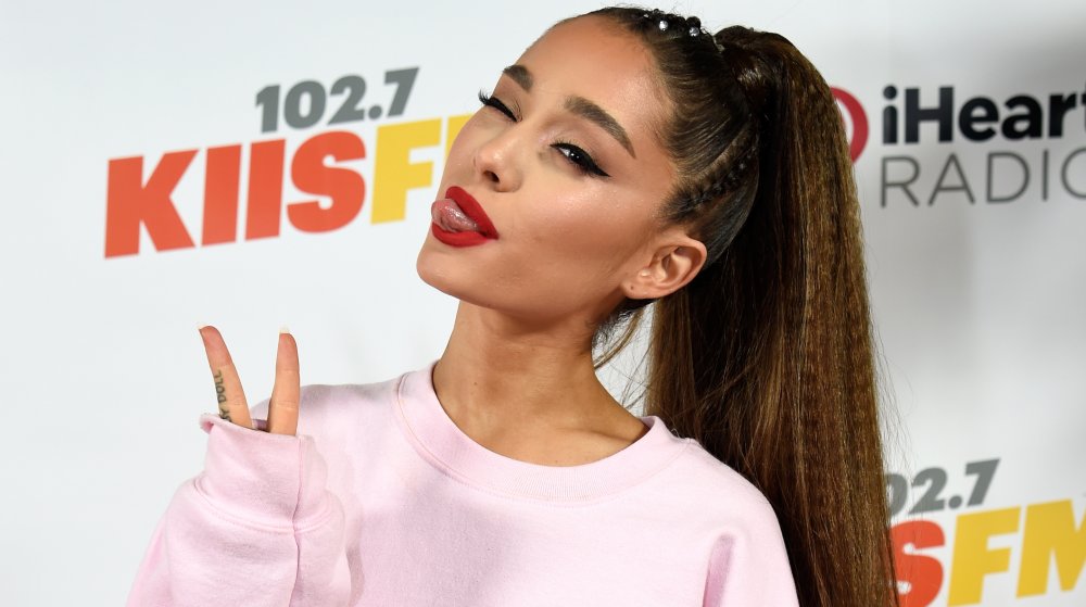 Ariana Grande con la sua coda di cavallo, lanciando un segno di pace