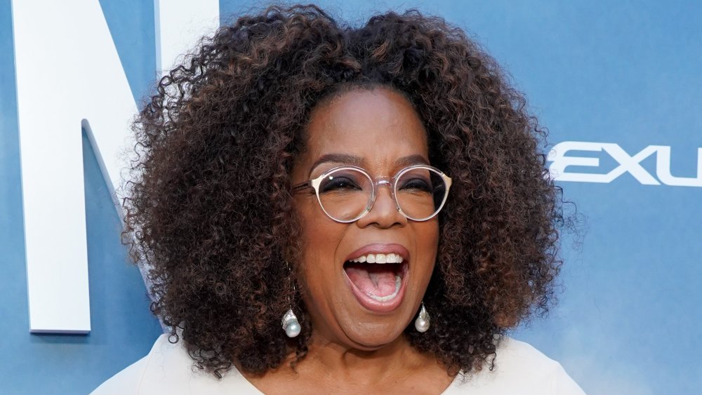 Oprah Winfrey in abito bianco, ridendo sul tappeto rosso