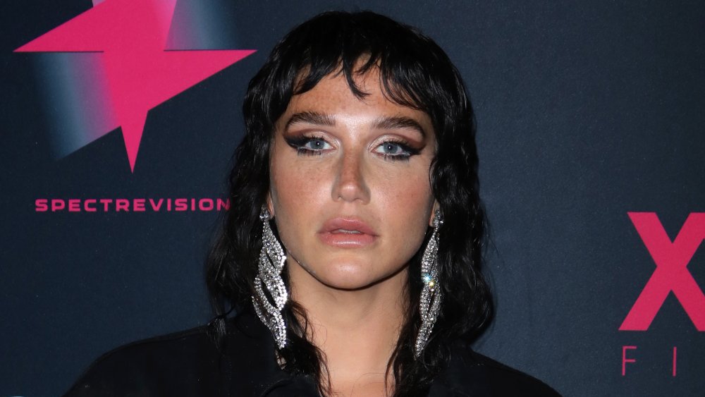 Kesha with black hair and big silver earrings