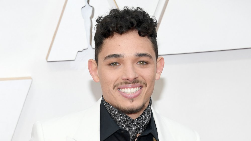 Anthony Ramos smiling in front of white wall