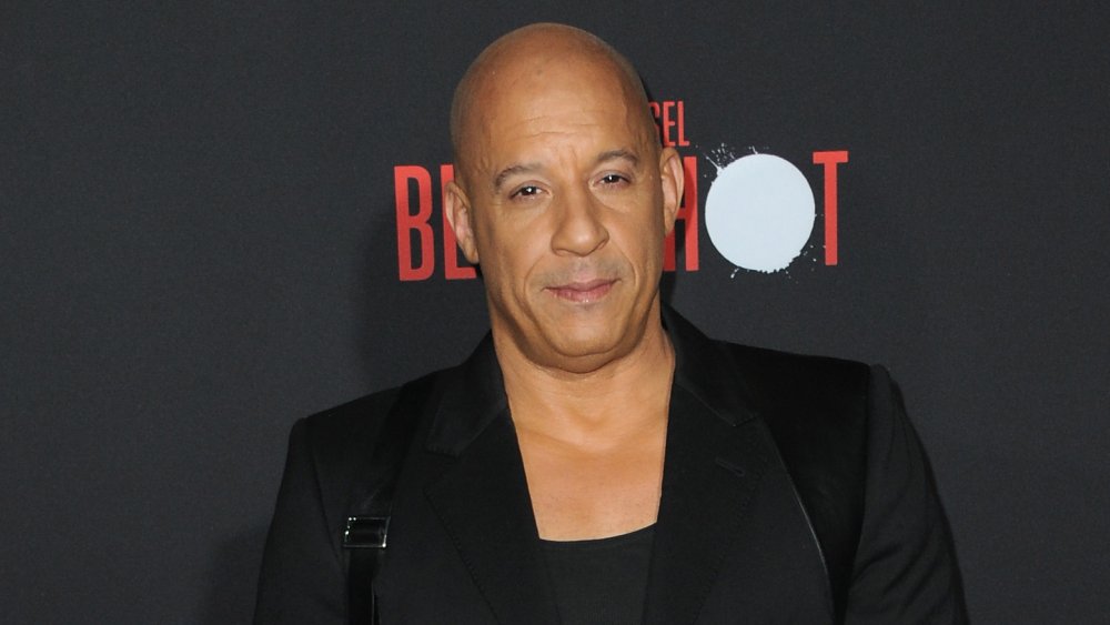 Vin Diesel in an all black ensemble in front of black wall