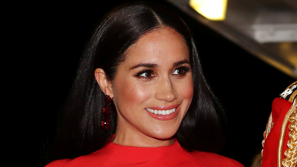 Meghan Markle, la duchessa del Sussex, vestita di rosso brillante durante un evento