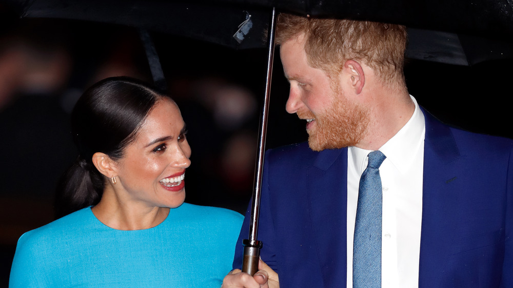 Meghan Markle e il principe Harry si sorridono sotto l'ombrellone