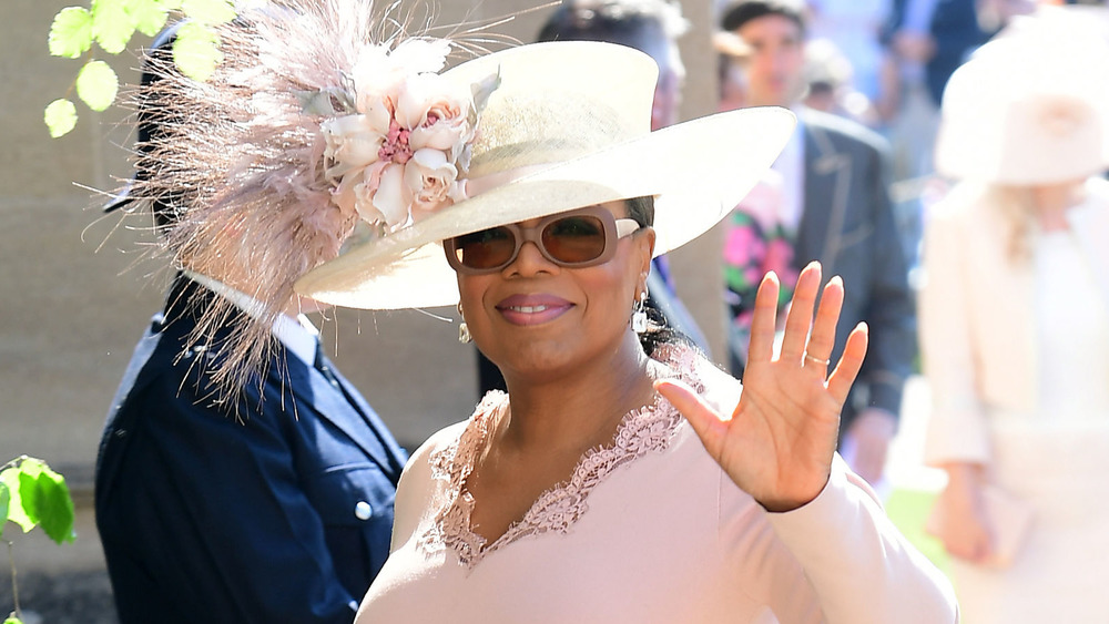 Oprah Winfrey in un grande cappello di piume e occhiali da sole che sventolano 