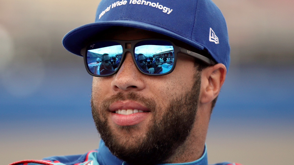 Bubba Wallace in tonalità riflettenti blu guarda la folla prima di una gara