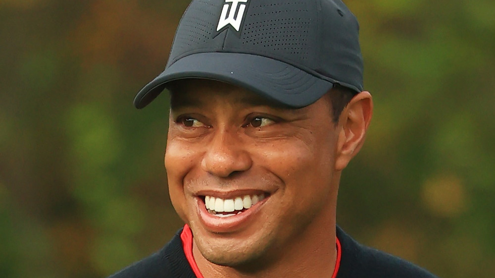 Tiger Woods, sorridente, con indosso il berretto, giocando a golf 