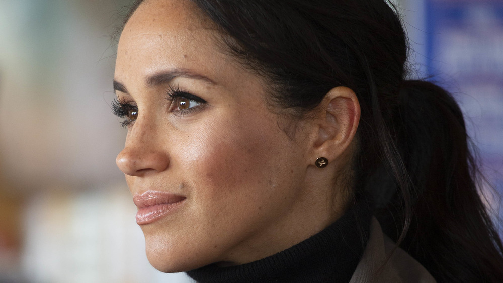 Meghan Markle guarda lontano indossando una coda di cavallo