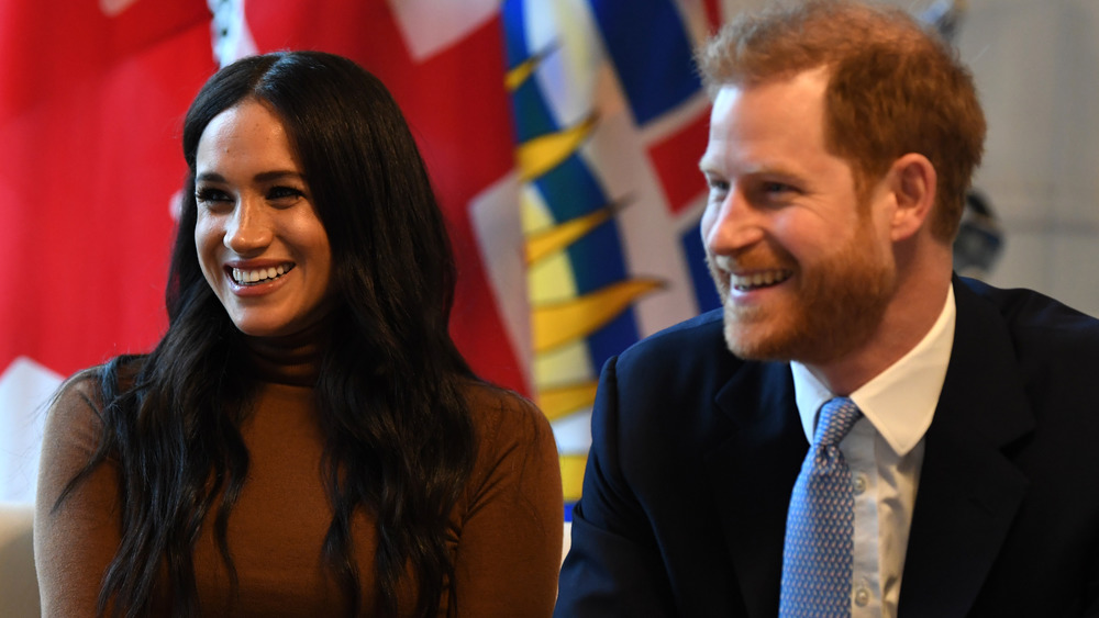 Meghan Markle e il principe Harry sorridono mentre si siedono