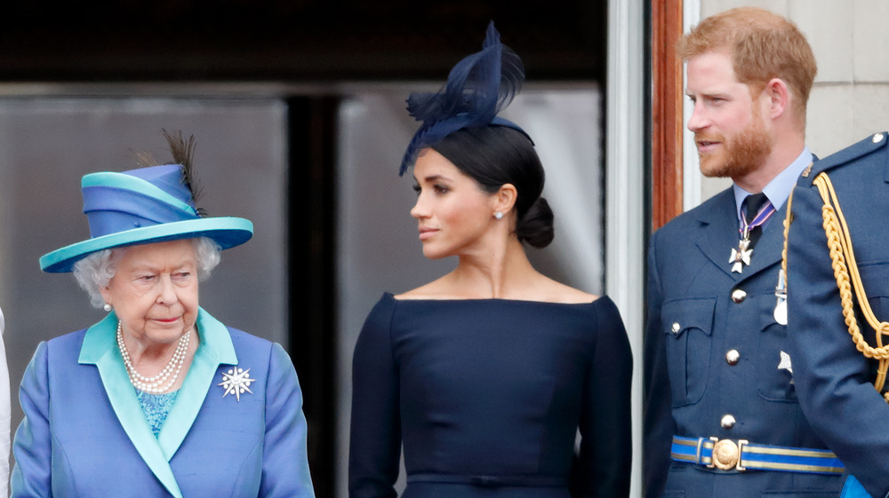 La regina Elisabetta, Meghan Markle e il principe Harry in piedi uno accanto all'altro su un balcone 