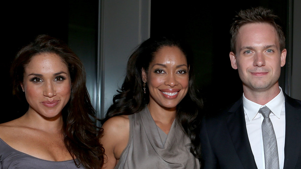 Meghan Markle, Gina Torres e Patrick J. Adams sorridono