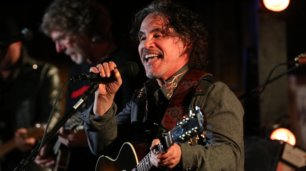 John Oates di Hall & Oates sorride e canta in un microfono 