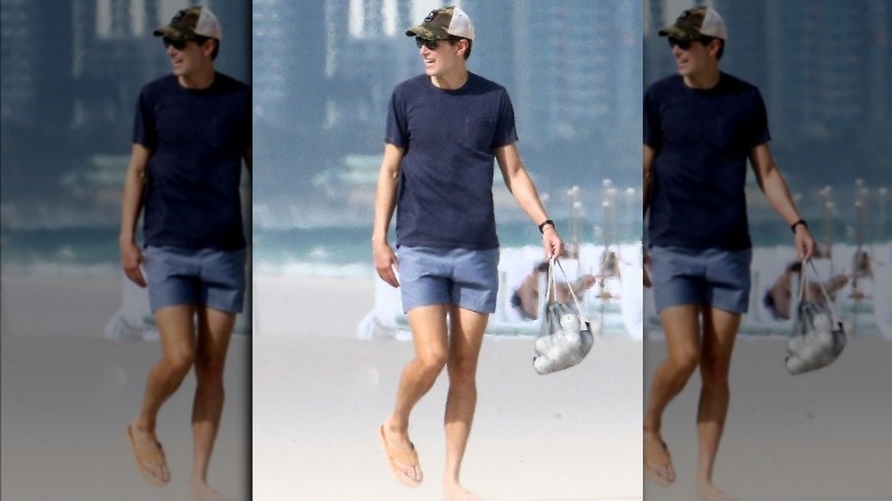 Jared Kushner sulla spiaggia sorridente, in costume da bagno e sandali 