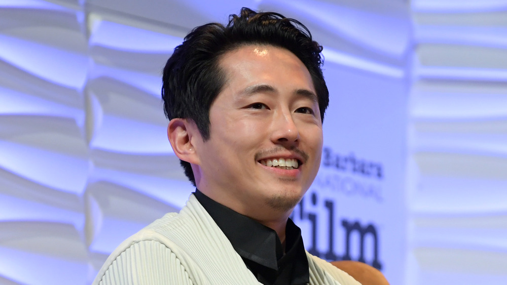 Steven Yeun sorride sul palco